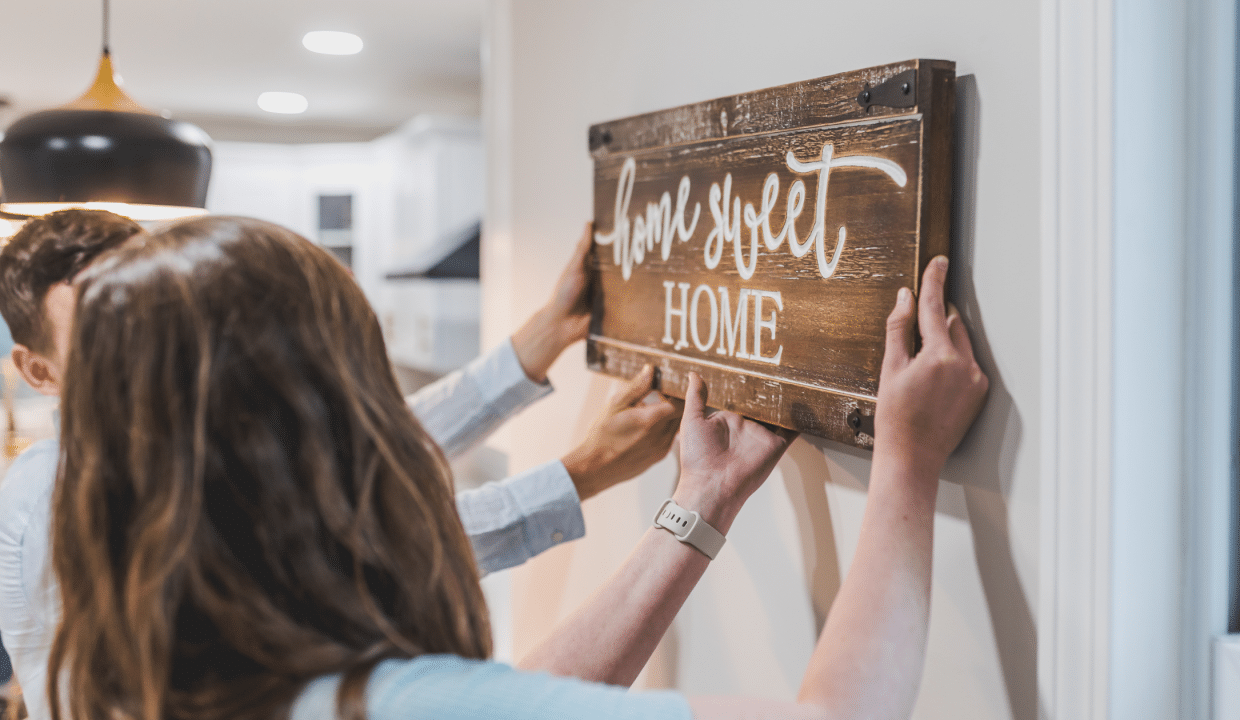 New homeowners hanging a sign in their home